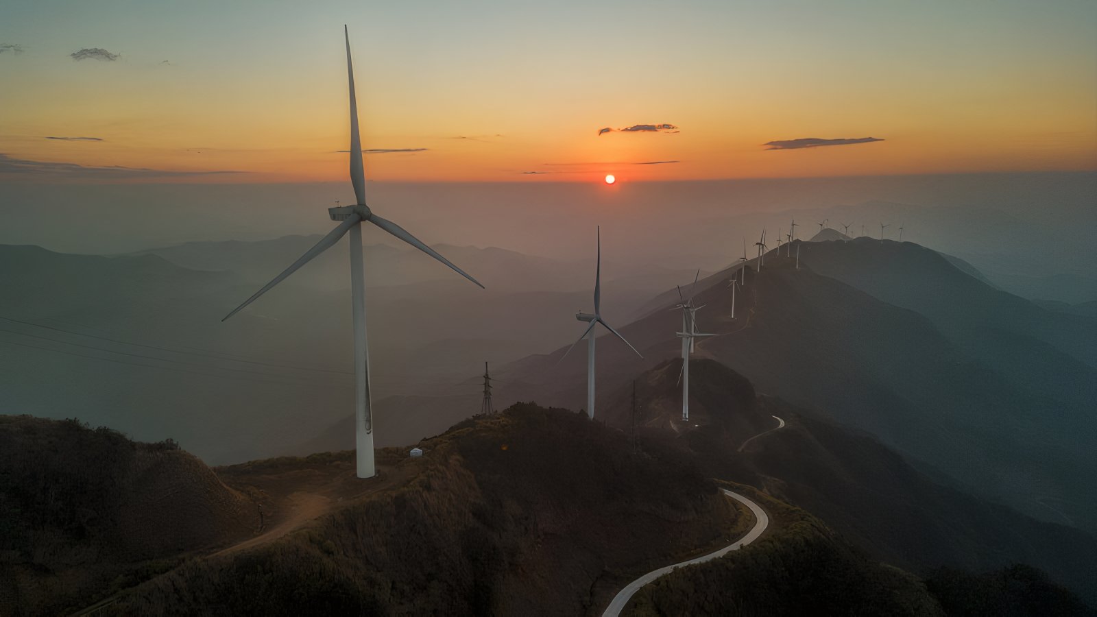 Wind turbines on a mountain ridge at sunset — representing the environmental engineering and sustainability dimension of the water-treatment vertical